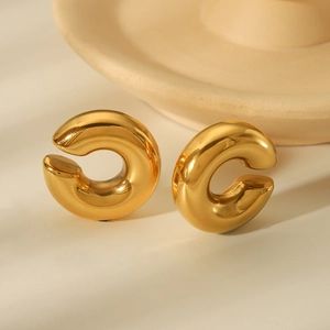 Macro shot of minimalist thick C-shaped gold hoop earrings with a mirror polished finish