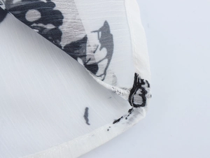 Detailed macro view of high-quality stitching and black floral print on white chiffon fabric