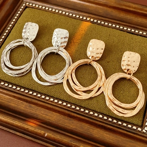 Detail of gold and silver geometric earrings displayed in a vintage wooden frame