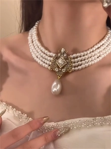 Detail of four-layer pearl choker with vintage gold pendant and drop pearl