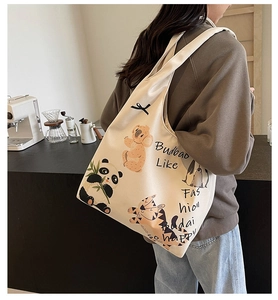 Close-up of beige canvas tote bag with animal illustrations and black bow detail