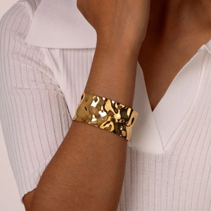 Close-up of golden stainless steel wide cuff bracelet with irregular textured finish on wrist