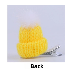 Detail view of mini yellow knitted hat hair clip with white pompom on metal duckbill clip