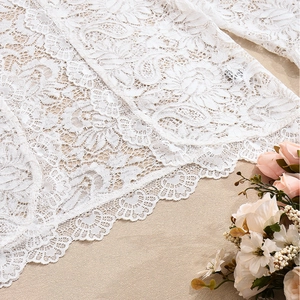 Close-up of intricate floral lace texture and delicate embroidery on white elegant top