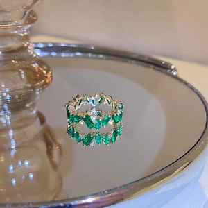 Bague dorée sertie de zircons verts taille baguette sur plateau miroir brillant