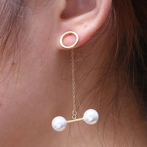 Detail of elegant gold tassel earrings featuring delicate chains and double pearls on a model