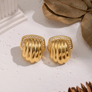 Detail of gold textured shell earrings with sparkling rhinestones on a decorative base