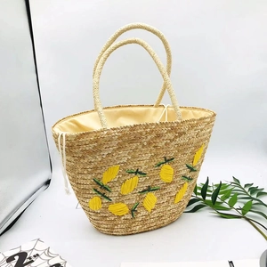 Detailed close-up of handmade straw tote bag featuring yellow lemon embroidery and drawstring