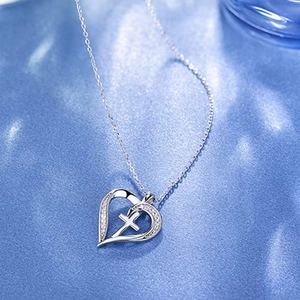 Silver heart cross pendant necklace with diamonds on blue silk background