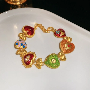 Detail of vintage style golden bracelet with multi-colored enamel heart charms and gems