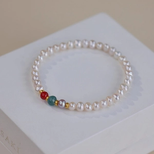Detail shot of white freshwater pearls and colorful stones on a white jewelry box