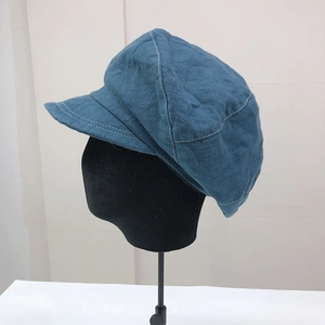 Vista laterale dettagliata di un berretto newsboy blu con cuciture bianche a contrasto