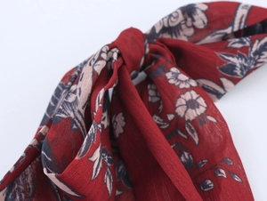 Gros plan sur le tissu en mousseline avec des motifs floraux rétro rouge foncé