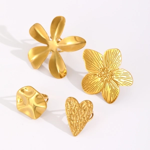 Detail view of four gold-plated stainless steel rings with floral, heart and geometric textures