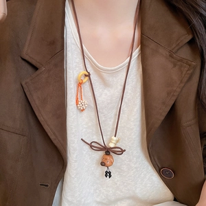Close-up of a brown wooden bear pendant necklace worn with a brown vintage jacket