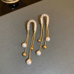 Detail view of gold tassel earrings with shimmering crystals and elegant white pearls