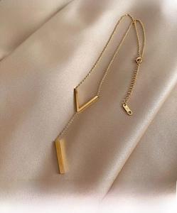 Close-up of golden V-shaped pendant necklace on elegant champagne silk background