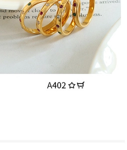 Detail shot of gold minimalist rings with red, green and white inlaid gemstones
