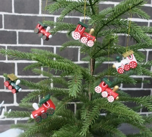 Close-up of 6-piece red and white wooden Christmas train ornaments hanging on a tree