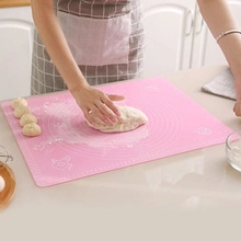Pink silicone baking mat with measurement scales for kneading dough in a kitchen setting