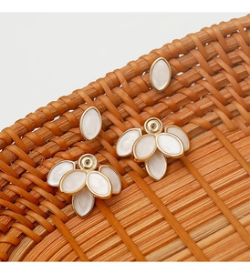 Detailed top view of vintage golden flower petal earrings on a woven bamboo tray