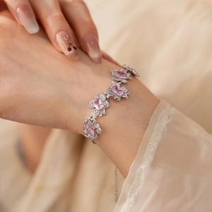 Silver bracelet with pink zircon flower and bow details on model wrist