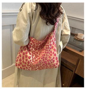 Pink leopard print canvas tote bag shown worn over a beige coat in a cozy room