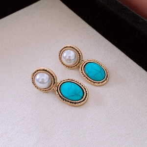 Macro shot of vintage style earrings with pearl and turquoise in gold finish
