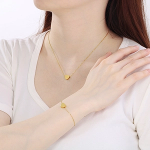 Gros plan sur un ensemble de collier et bracelet cœur plaqué or 18k sur un mannequin