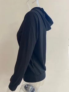 Detalle de sudadera con capucha negra con textura de punto acanalado y mangas largas