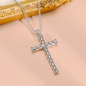 Detail of silver bamboo joint cross pendant with box chain on pink background