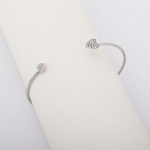 Detail of silver open bangle featuring double heart charms with crystal rhinestones