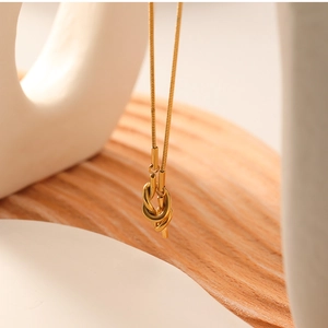 Macro shot of 18K gold sailor knot pendant on a delicate snake chain necklace