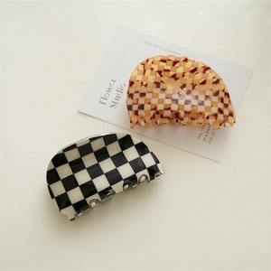 Detail of checkered acetate hair claws with premium glossy finish and strong grip design