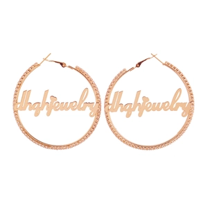 Détail de créoles personnalisées en or rose avec zircons blancs et design de nom