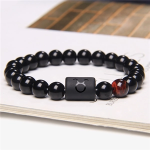 Macro detail of Taurus zodiac bracelet featuring black onyx beads and red tiger eye stone