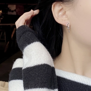Close-up of asymmetrical liquid silver stud earring on female model ear