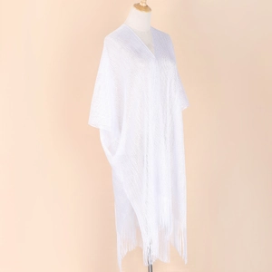 Detail of white knitted shawl featuring a stylish fringe hem on a studio mannequin