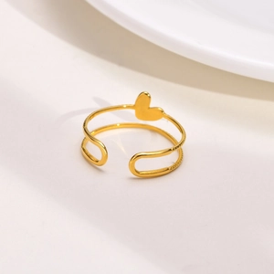 Bague ouverte double couche plaquée or 18 carats avec breloque cœur sur fond blanc