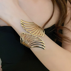Macro shot of gold hollow leaf arm cuff bracelet with intricate metal wing design