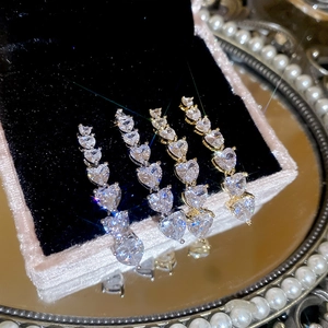 Detail shot of 18K gold and silver heart earrings with zircons on black velvet tray