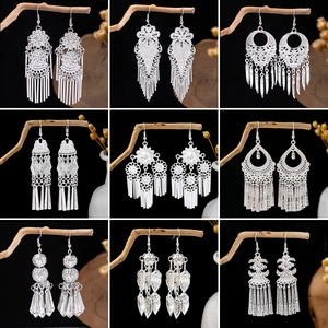 Macro shot of silver bohemian drop earrings with hollow flowers and tassels on branches