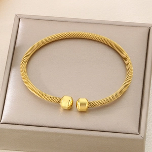 Macro detail of golden mesh woven open bangle with textured stripe sphere accents