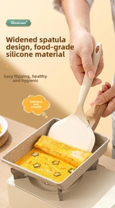 Gros plan d'une spatule large en silicone retournant une omelette dans une poêle à tamagoyaki