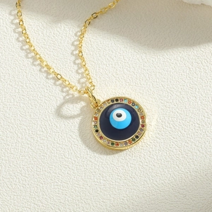 Detail of golden Evil Eye pendant featuring multicolored zircon stones on a circular charm