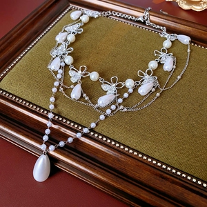 Detailed macro view of retro multi-layer pearl necklace with elegant diamond butterfly pendant