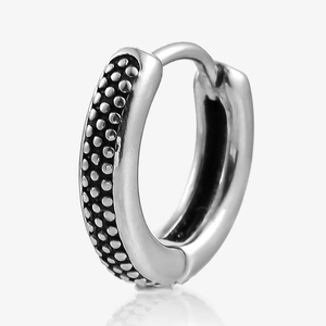 Macro detail of retro silver hoop earring with granular texture and antique finish