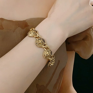 Gros plan d'un bracelet gourmette doré tête de lion vintage porté sur un poignet élégant