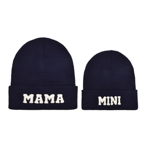 Dettaglio dei berretti in maglia blu scuro per genitore e bimbo con ricamo Mama e Mini