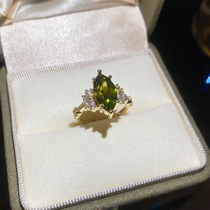 Macro detail of 14K gold plated marquise green emerald ring in luxury jewelry box